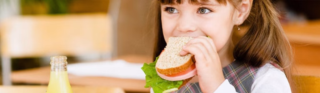 طفلة تتناول وجبتها بشهية لمعرفتها بأهمية تغذية الطفل في المدرسة